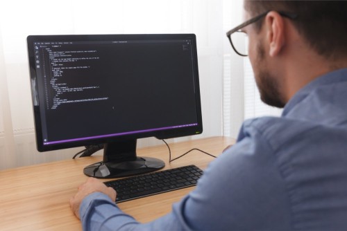 programmer-in-glsses-typing-new-lines-of-html-code.jpg